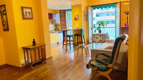 Il comprend un salon avec des murs jaunes, un canapé et une cuisine. dans l'établissement Chaleureux appartement, à Nice