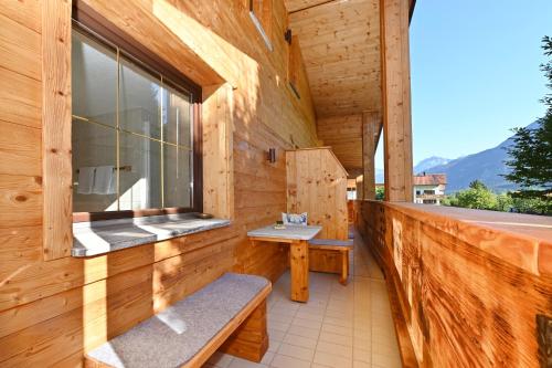 a wooden building with a balcony with benches and a window at Hotel Die Montafonerin in Vandans