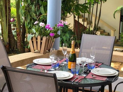 a table with a bottle of wine and glasses on it at 1 bedroom Villa on Ao Yon beach with sea views in Phuket Town