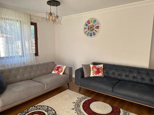 een woonkamer met 2 banken en een tapijt bij Uzungöl city evleri in Dernekpazarı