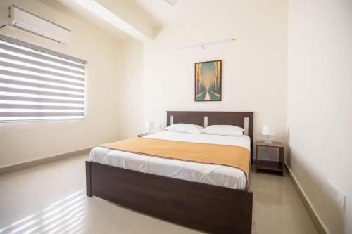 a bedroom with a large bed in a white room at Neemtree Apartments in Hyderabad