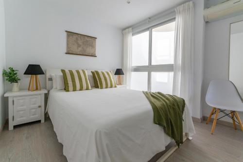 a white bedroom with a white bed and a window at Amplio apartamento recién reformado in La Playa de Arguineguín