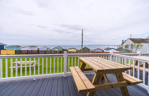 a wooden picnic table on a deck with houses at Lundy Sea View Villa - Mobility friendly in Bideford
