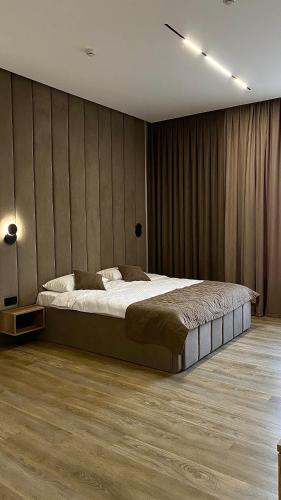 a bedroom with a large bed and a wooden floor at Гостинично-банный комплекс PARADISE in Shchūchīnsk