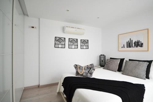 a white bedroom with a bed with black and white pillows at Luminoso loft recién reformado in La Playa de Arguineguín