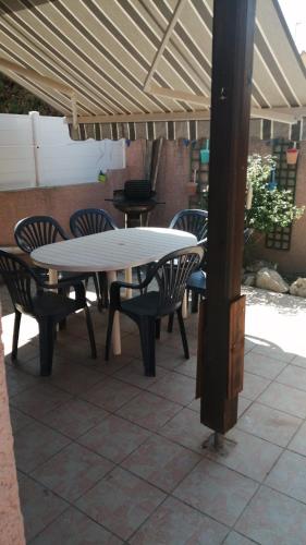 uma mesa branca e cadeiras sentadas sob um telhado em Villa Vias Plage em Vias