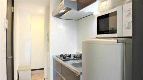 eine weiße Küche mit einer Spüle und einer Mikrowelle in der Unterkunft Credo Maison Kamakura - Vacation STAY 10347 in Kamakura