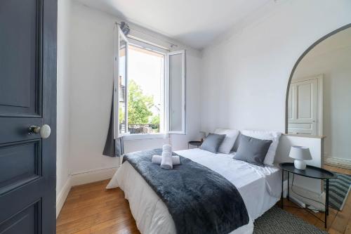 une chambre blanche avec un lit avec une fenêtre dans l'établissement Le Rue Neuve - Appartement Calme et lumineux, à Vichy