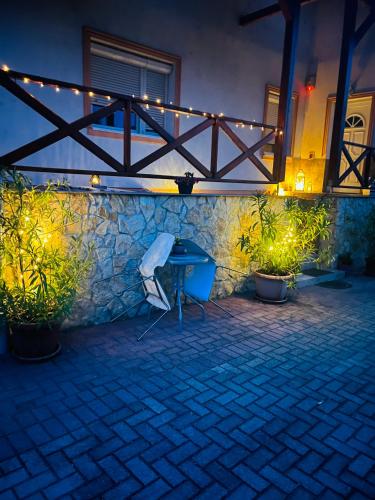 a table and a chair in a patio at night at Szandra Vendégház in Öskü