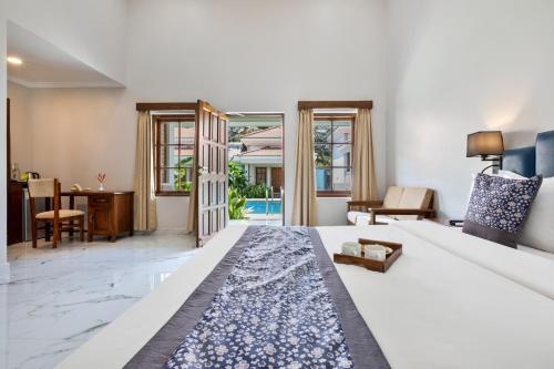 a bedroom with a large white bed and a living room at Leoney Resort Goa in Vagator