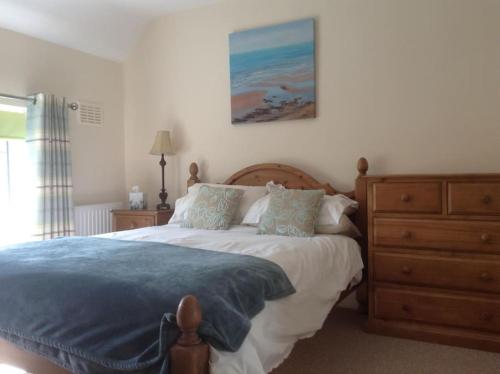 a bedroom with a large bed and a dresser at Lynn Cottage, Newport in Newport
