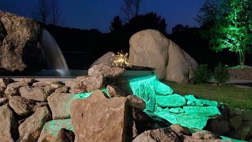a waterfall and rocks in a garden at night at As Penedas, Casa dos Arcos in Sober
