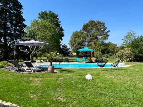 a pool with chairs and umbrellas in a yard at l'Atelier des rêves in Morizès