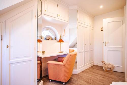 um quarto com armários brancos, uma cadeira e um espelho em Haus-Munkhoog em Munkmarsch