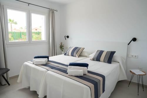 two beds in a white room with a window at Villas Rymar in Cala en Bosc