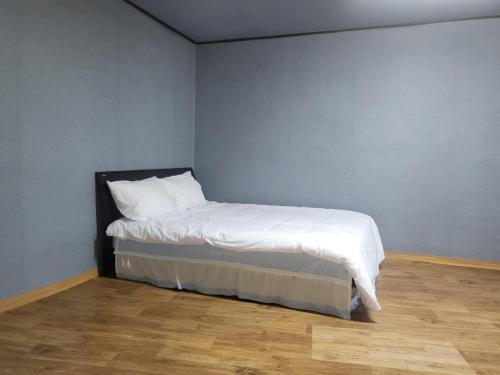 a small bedroom with a bed with white sheets at Songwol Park in Sokcho