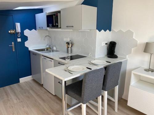 een keuken met een aanrecht met 2 stoelen en een wastafel bij Studio moderne en plein centre de Caen in Caen