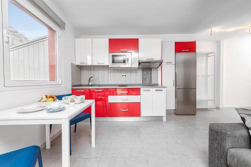 a kitchen with red and white cabinets and a table at Sol Mogan Suites - Adults Only in Puerto de Mogán