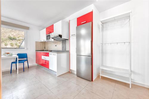 a kitchen with red cabinets and a stainless steel refrigerator at Sol Mogan Suites - Adults Only in Puerto de Mogán