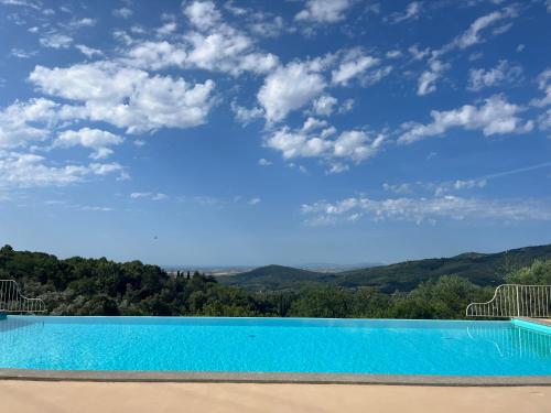 een zwembad met een blauwe lucht en bergen bij Agriturismo il Ghiaccio in Suvereto