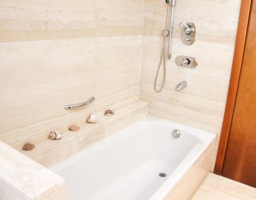 a white bath tub with a shower with a shower head at Luxury Breathtaking Seafront Penthouse Duplex in Rishon LeẔiyyon