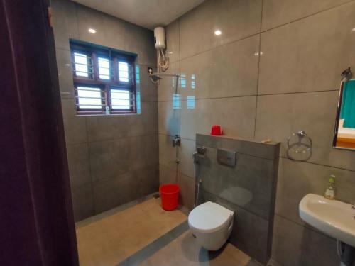 a bathroom with a toilet and a shower and a sink at Nandhanam Holidays in Kannur