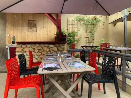 a table and chairs with an umbrella in a restaurant at Hôtel Restaurant de l'Union in Mirambeau
