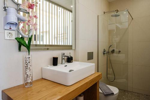 a bathroom with a sink and a glass vase with flowers at Addimare Sea View Villa, and Events Venue in Alykes