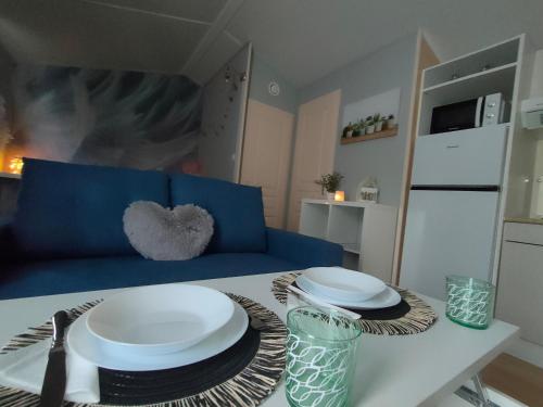 a living room with a table with plates and a blue couch at Naturalayos I y Naturalayos II - casas para parejas - jacuzzi in Pelayos de la Presa