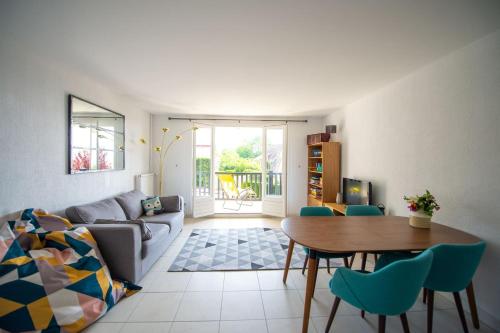 un salon avec un canapé, une table et des chaises dans l'établissement Appartement avec terrasse vue mer Trouville sur mer, à Trouville-sur-Mer