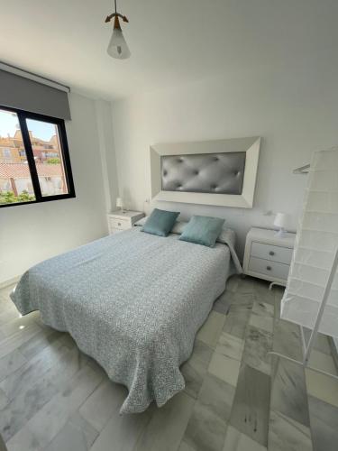 una camera bianca con un grande letto con cuscini blu di Apartamento Jardines del Rocío a Torre del Mar