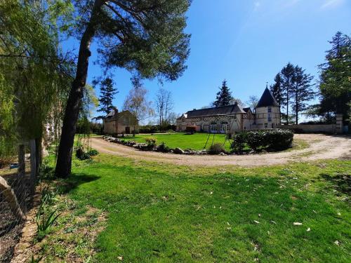 a house in the middle of a yard with a driveway at La Tour de rêves in Beaumont-la-Ronce
