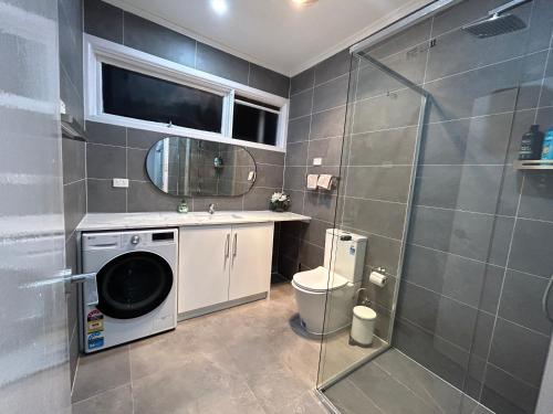 uma casa de banho com uma máquina de lavar roupa e um chuveiro em Charming House; Walk to Beach & Shops em Rosebud