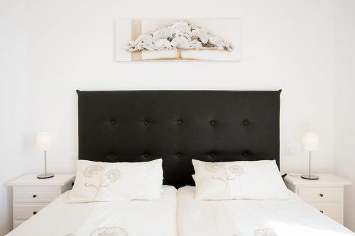 a bed with a black headboard and two white pillows at Casa Nancy in Puerto Calero
