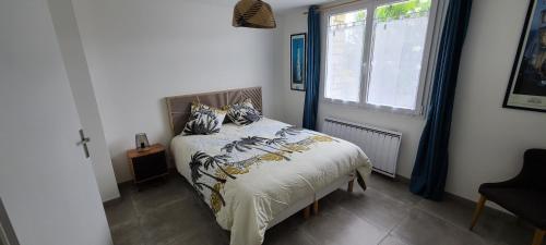 a bedroom with a bed and a window at Les Geais Bleus in Royan