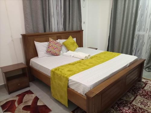 NYALI LUXURY APARTMENT في مومباسا: غرفة نوم بسرير كبير مع بطانية صفراء