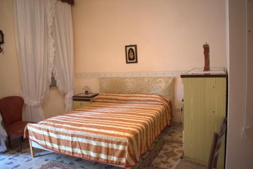 um quarto com uma cama com um cobertor listrado e uma cómoda em Appartamento ammobiliato em Pietraperzia