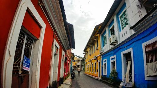 a person riding a bike down a street with colorful buildings at Heritage Village Resort & Spa Goa in Cansaulim