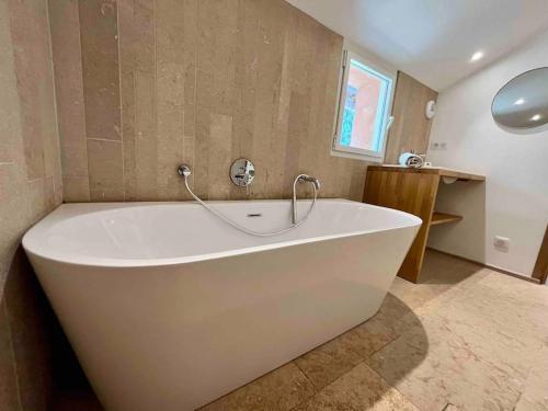 La salle de bains est pourvue d'une grande baignoire blanche. dans l'établissement Villa Masa au calme vue colline et aperçu sur la mer, aux Lecques