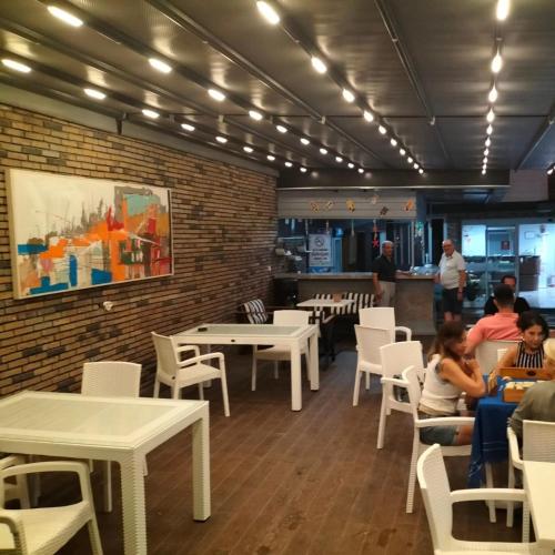 a restaurant with white tables and chairs and a brick wall at Hotel Simsek in Finike