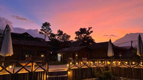 a sunset over a house with a fence and umbrellas at S Plus Bungalow in Sa Pa
