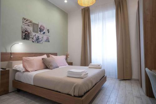 a bedroom with a bed with white sheets and pink pillows at Taty Home Casa Vacanze in Salerno