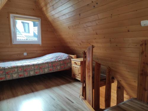 una camera da letto in stile baita di tronchi con letto e finestra di Za potokiem a Solina