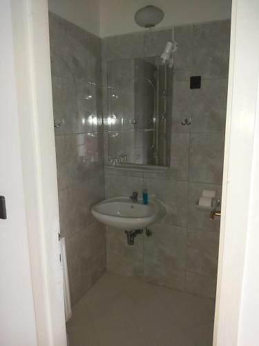 W łazience znajduje się umywalka i lustro. w obiekcie Valcsics Villa Panzió w mieście Pecz