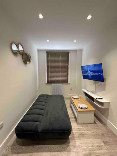 um quarto com uma grande cama preta e uma mesa em Stylish and cozy flats em Londres