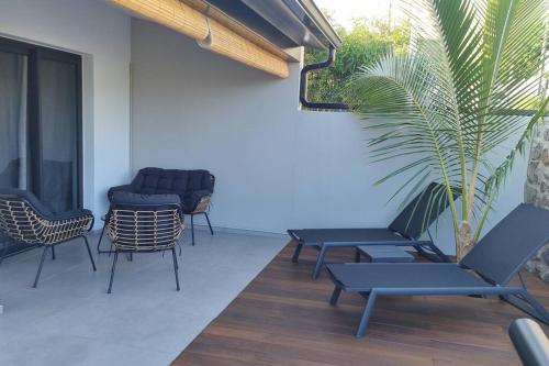 a patio with chairs and tables and a palm tree at Villa standing 50 in Ravine des Cabris