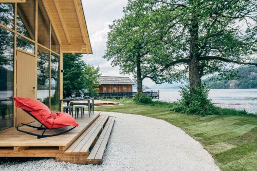 Eco Lodges Millstätter See في دوبرياخ: منزل به كرسي احمر يجلس على الشرفة