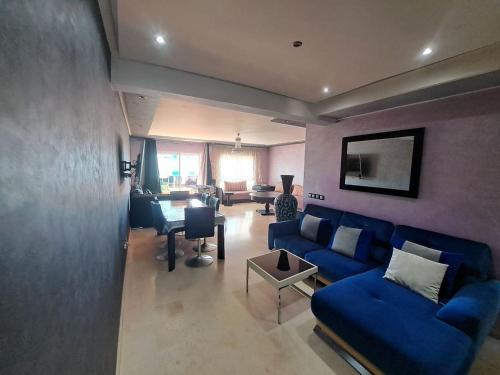 uma sala de estar com um sofá azul e uma mesa em très bel appartement avec piscine em Minaret de Mansuria