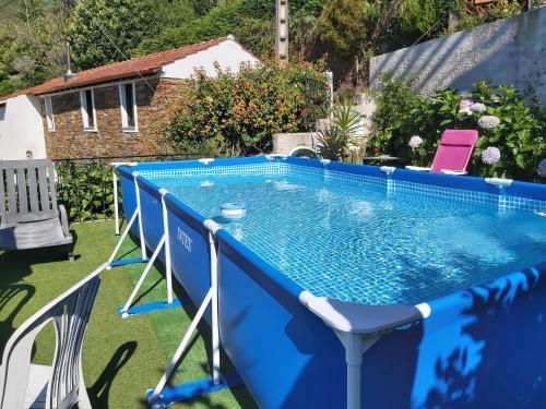 a blue swimming pool with chairs around it at Casa de Xisto in Arganil