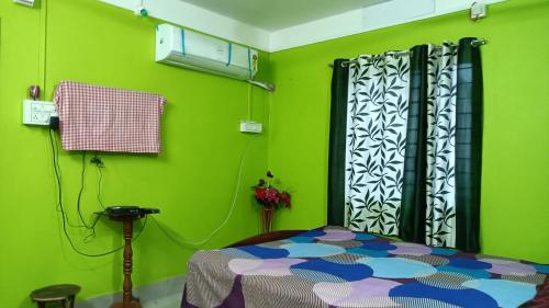 - une chambre avec des murs verts et un lit dans un dortoir dans l'établissement Shanti Kunj Homestay, à Agartala